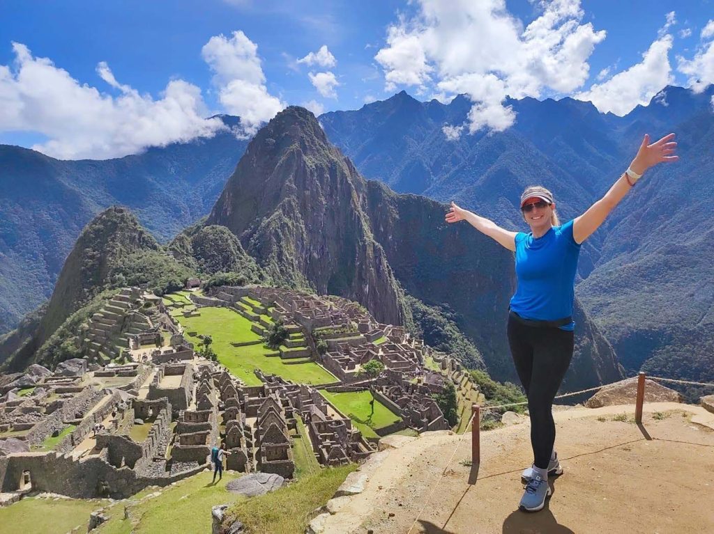 Traveler celebrating at the summit of Machu Picchu Mountain, part of Machu Picchu Circuits, with panoramic views of the citadel below