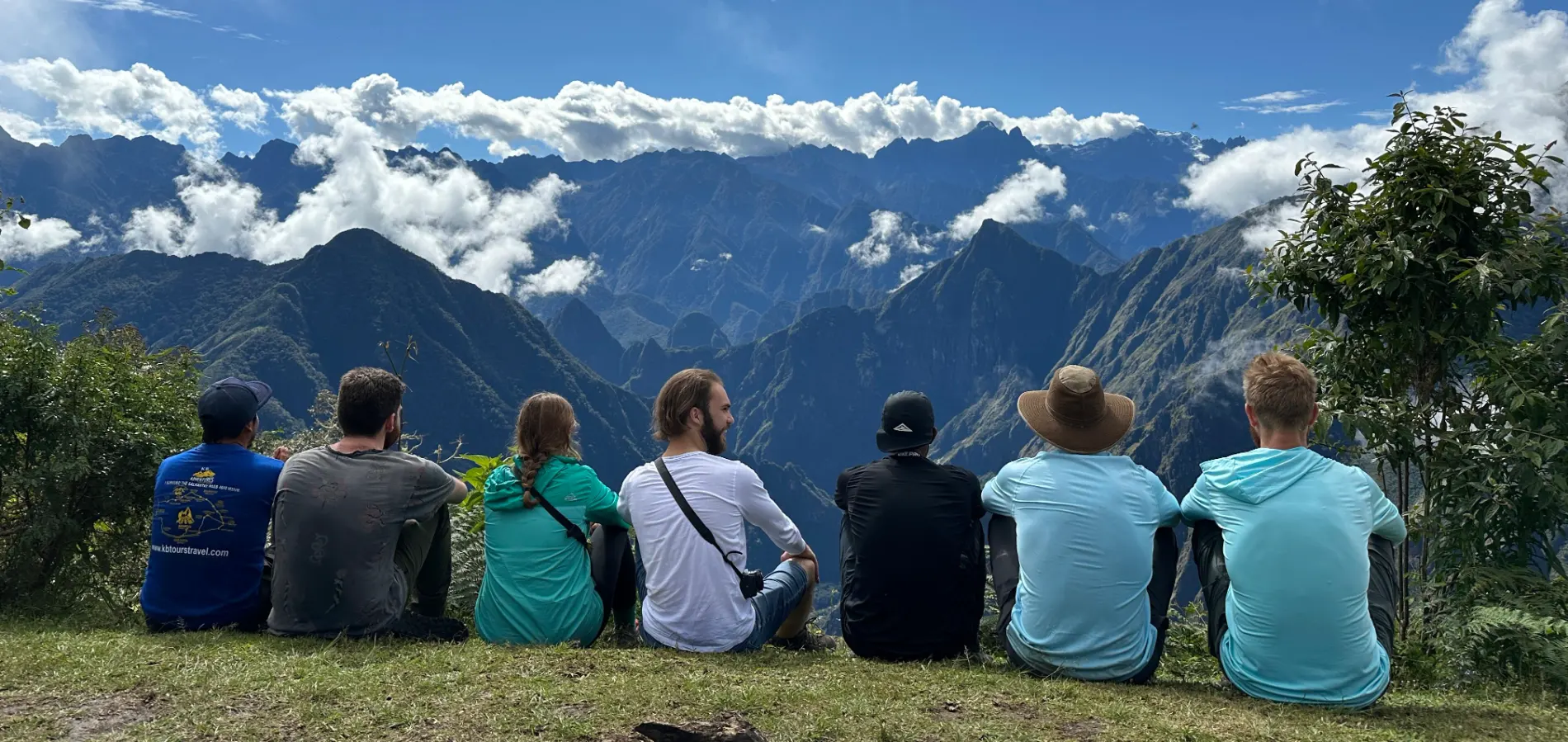 Group of trekkers resting on a mountain trail in Peru, overlooking dramatic Andean peaks and valleys during a private trekking experience.