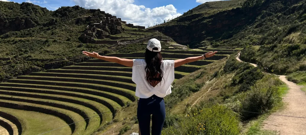 Traveler enjoying the view of the Pisac Archaeological Site with Inca terraces and ruins in the Sacred Valley, Peru